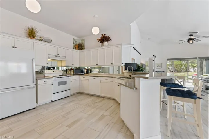 Kitchen featuring hanging light fixtures, white cabinets, white appliances, and kitchen peninsula