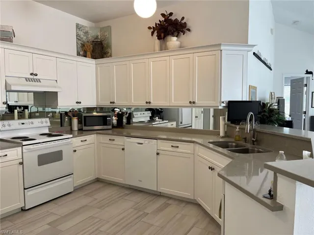Kitchen featuring white cabinetry, sink, white appliances, and kitchen peninsula