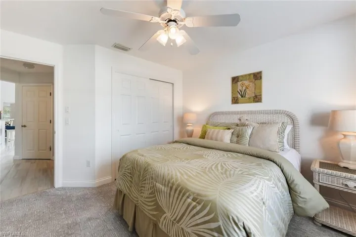 Bedroom with ceiling fan, light carpet, and a closet