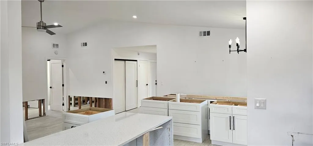 Kitchen with ceiling fan, light hardwood / wood-style floors, hanging light fixtures, and white cabinets