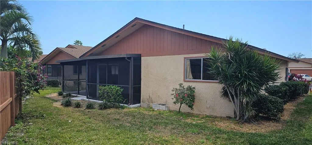 Rear view of house with a lawn and a sunroom