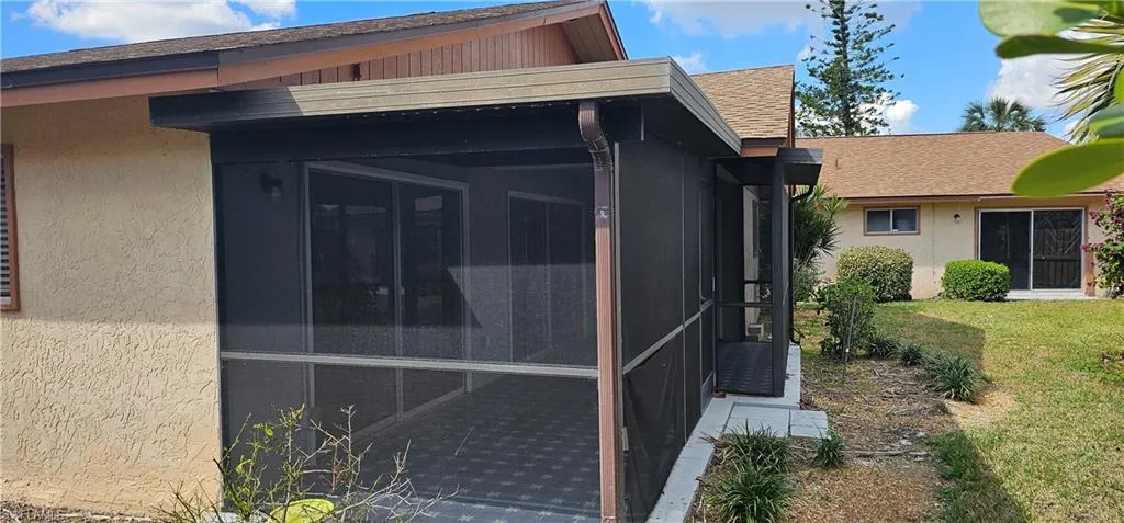 View of side of property with a sunroom and a lawn