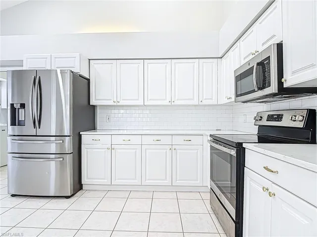 Kitchen featuring light countertops, light tile patterned floors, white cabinets, and stainless steel appliances