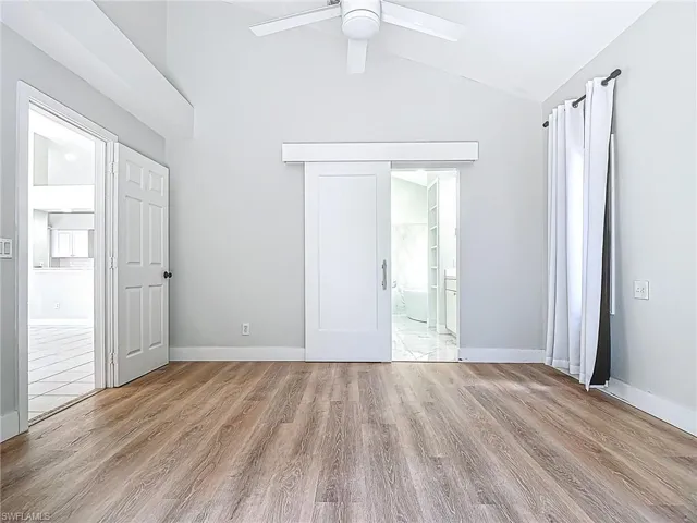 Spare room featuring a ceiling fan, baseboards, vaulted ceiling, and wood finished floors