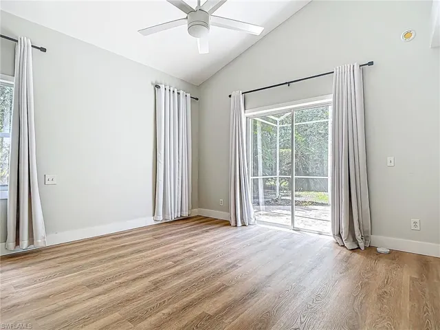 Spare room featuring plenty of natural light, a ceiling fan, light wood-type flooring, and lofted ceiling