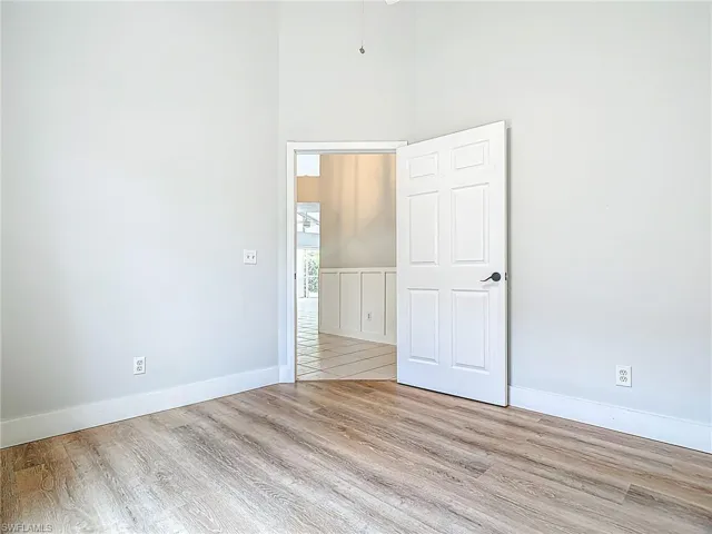 Spare room with baseboards, a high ceiling, and wood finished floors