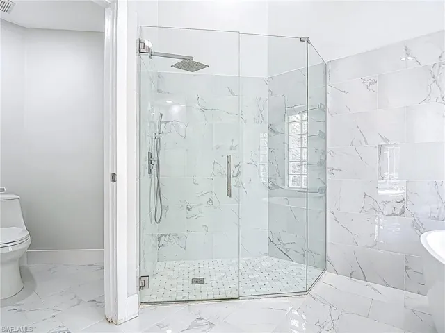 Full bath with toilet, baseboards, a marble finish shower, and marble finish floor