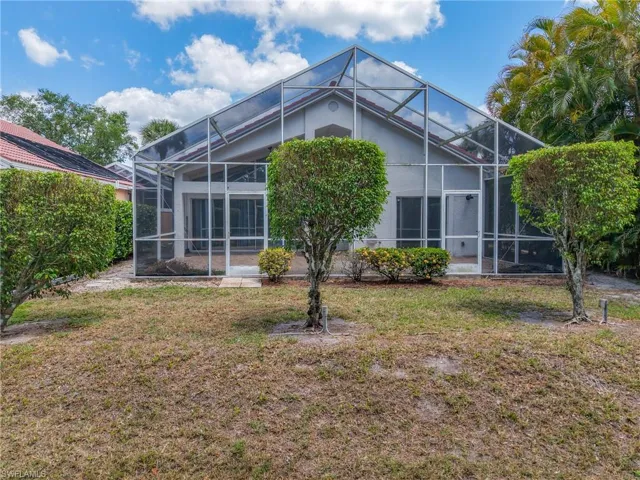 Back of property with a lawn and a lanai
