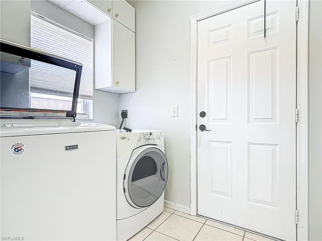 Laundry area featuring cabinet space, separate washer and dryer, baseboards, and light tile patterned floors