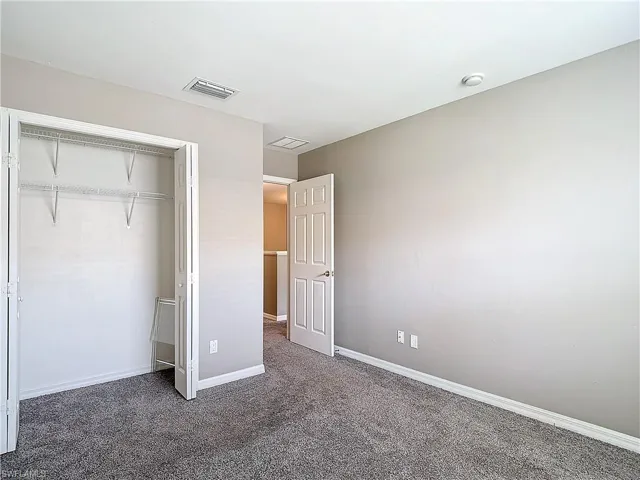 Unfurnished bedroom with a closet and dark carpet