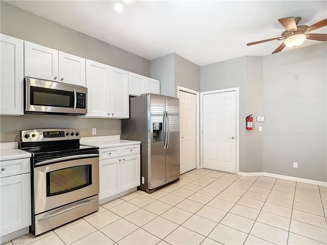 Kitchen featuring ceiling fan, stainless steel appliances, white cabinets, and light tile floors