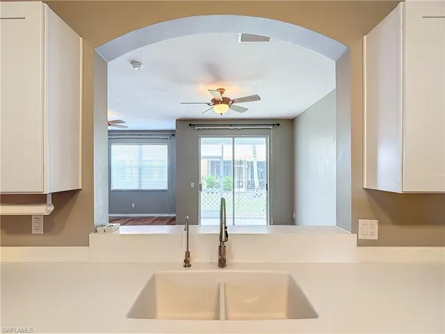 Kitchen with ceiling fan, sink, hardwood / wood-style floors, and white cabinetry