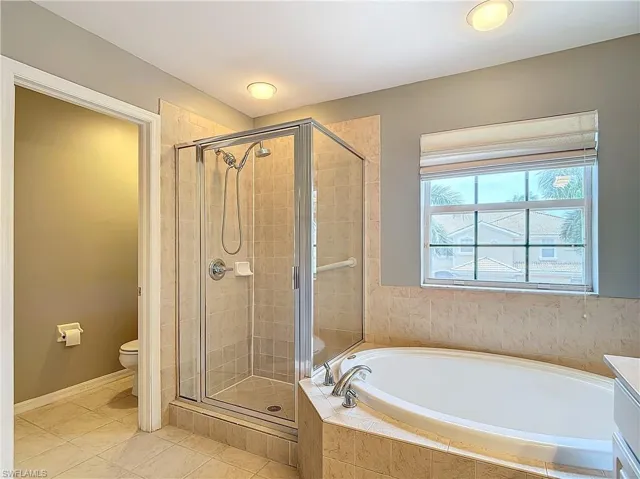 Full bathroom featuring tile flooring, separate shower and tub, toilet, and vanity