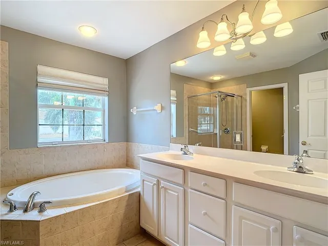 Bathroom featuring double vanity and separate shower and tub