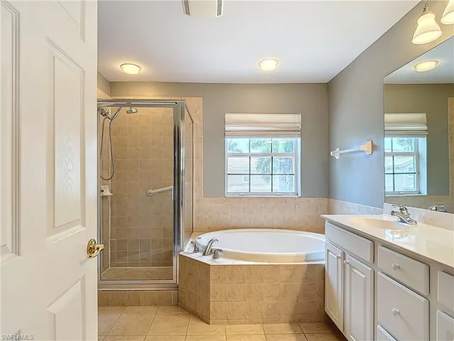 Bathroom featuring tile floors, large vanity, and independent shower and bath