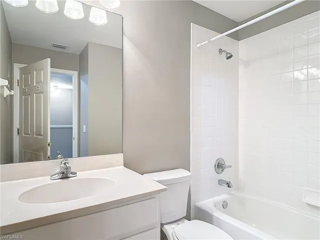Full bathroom featuring tiled shower / bath combo, large vanity, and toilet