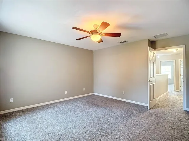 Spare room featuring carpet and ceiling fan