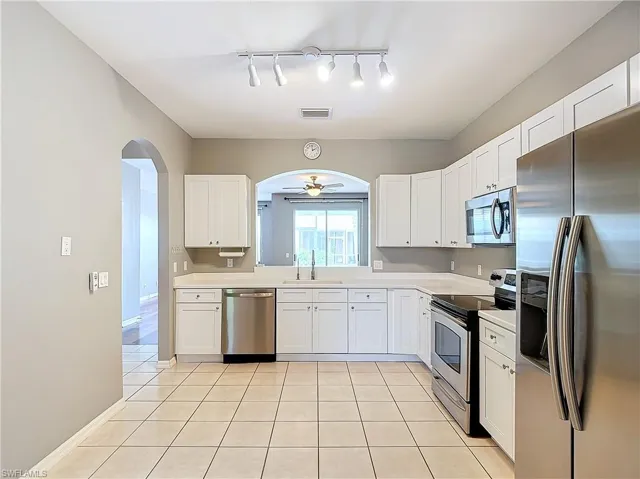 Kitchen featuring white cabinetry, appliances with stainless steel finishes, rail lighting, sink, and ceiling fan