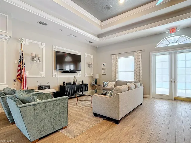 Living room featuring a tray ceiling, ornamental molding, french doors, and wood-type flooring