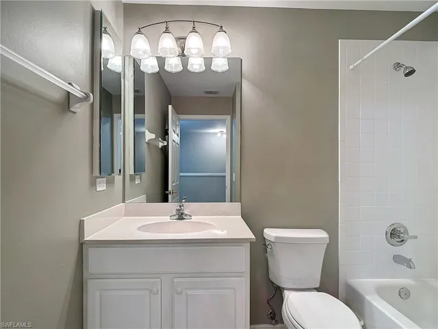 Full bathroom with tiled shower / bath combo, toilet, and vanity with extensive cabinet space