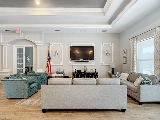 Living room with ornate columns, ornamental molding, and light hardwood / wood-style flooring