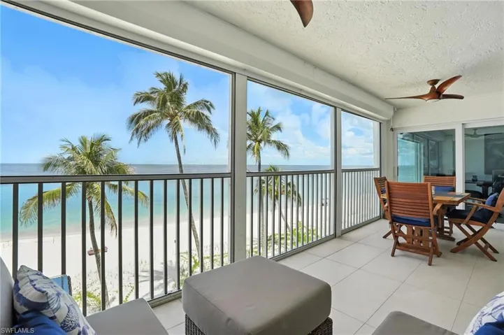 Sunroom with view of water and beach, a textured ceiling, and tile patterned floors