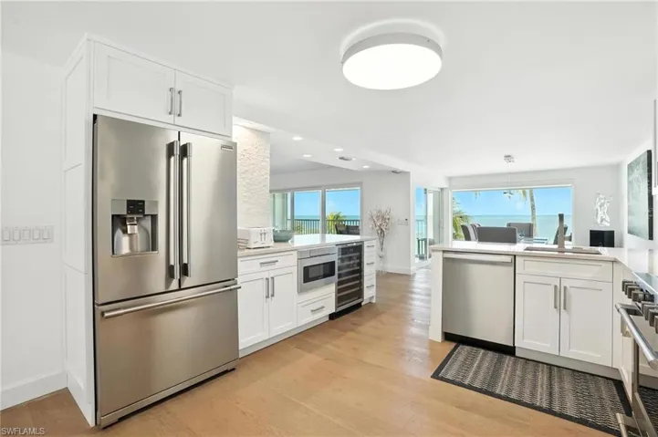 Kitchen featuring stainless steel appliances, wine cooler, light wood-style flooring, white cabinetry, and recessed lighting