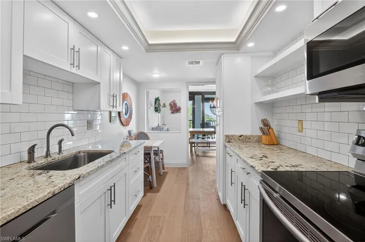 Kitchen featuring appliances with stainless steel finishes, open shelves, light wood finished floors, white cabinets, and recessed lighting