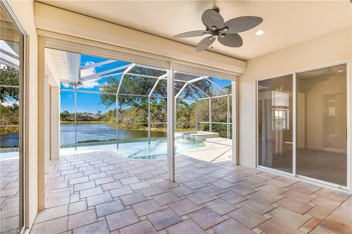 View of pool with a patio area, a sunroom, a ceiling fan, a water view, and a lanai