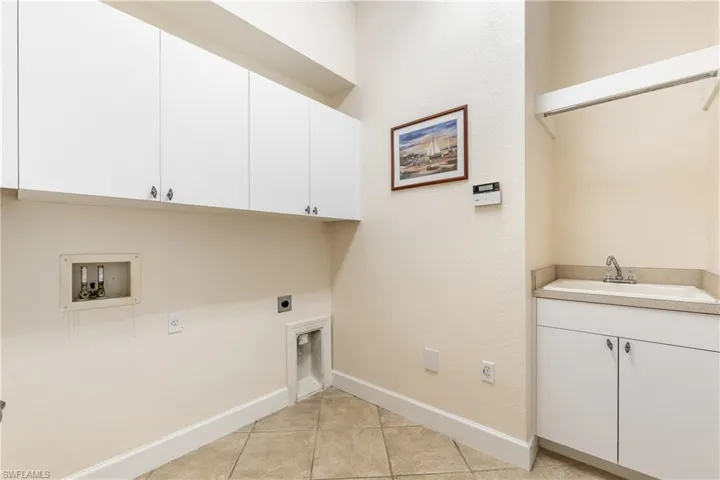 Laundry area with cabinet space, light tile patterned flooring, hookup for an electric dryer, and hookup for a washing machine