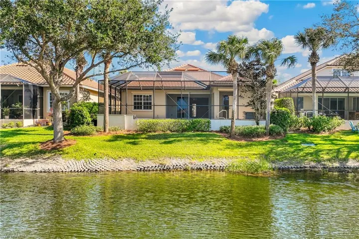 Rear view of property with a sunroom, glass enclosure, a water view, a tiled roof, and stucco siding