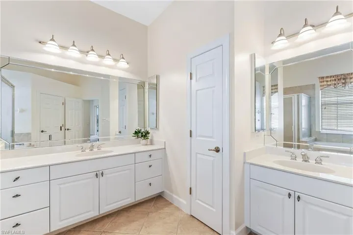 Full bathroom featuring two vanities, light tile patterned floors, a shower stall, and a garden tub
