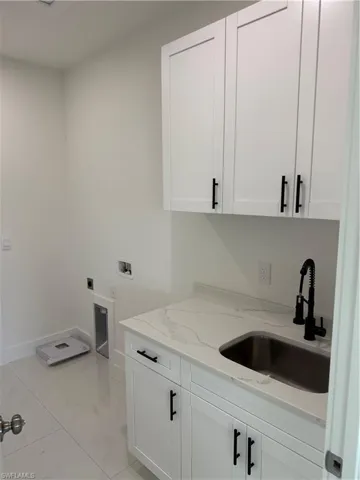 Washroom featuring cabinet space, light tile patterned floors, washer hookup, and hookup for an electric dryer