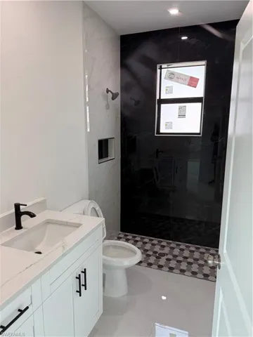 Bathroom featuring vanity, a marble finish shower, and light tile patterned flooring
