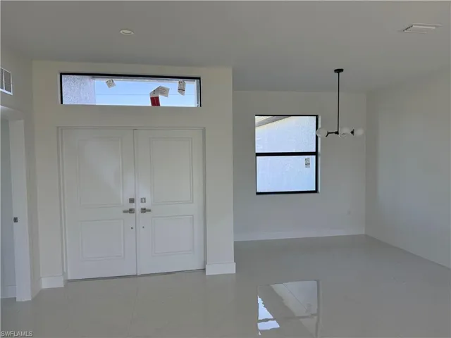 Foyer entrance with light tile patterned floors and a chandelier