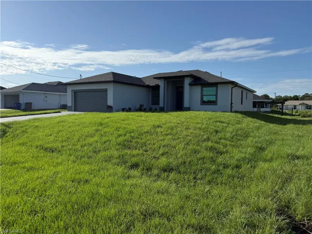 View of front facade featuring stucco siding, a garage, a front yard, and driveway