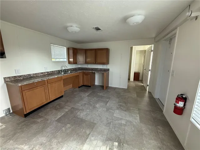 Kitchen featuring a sink, dark countertops, brown cabinetry, baseboards, and a textured ceiling