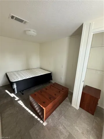 Bedroom with a textured ceiling and a closet