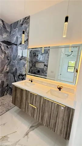Floating double vanity with integrated sinks, backlit mirror, and modern pendant lighting