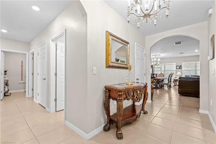 Hallway featuring arched walkways, hanging lights, and light tile patterned floors