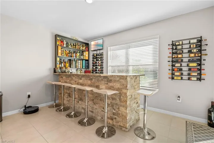 Indoor dry bar with baseboards and light tile patterned floors