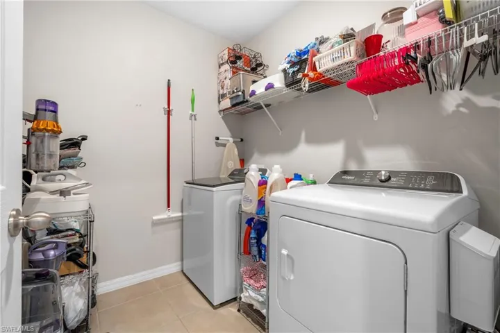 Laundry area with washing machine and clothes dryer and light tile patterned flooring