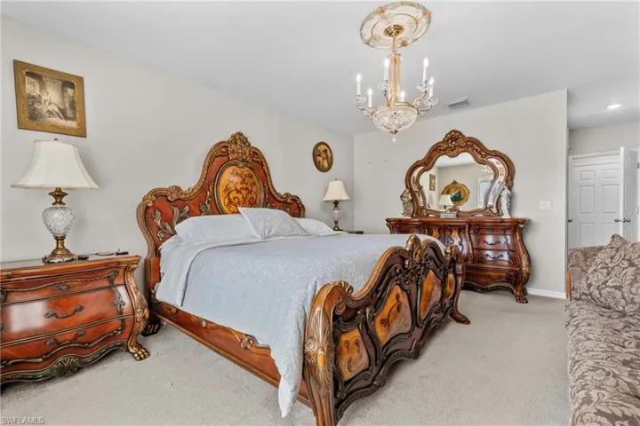 Bedroom featuring light colored carpet and suspended lighting
