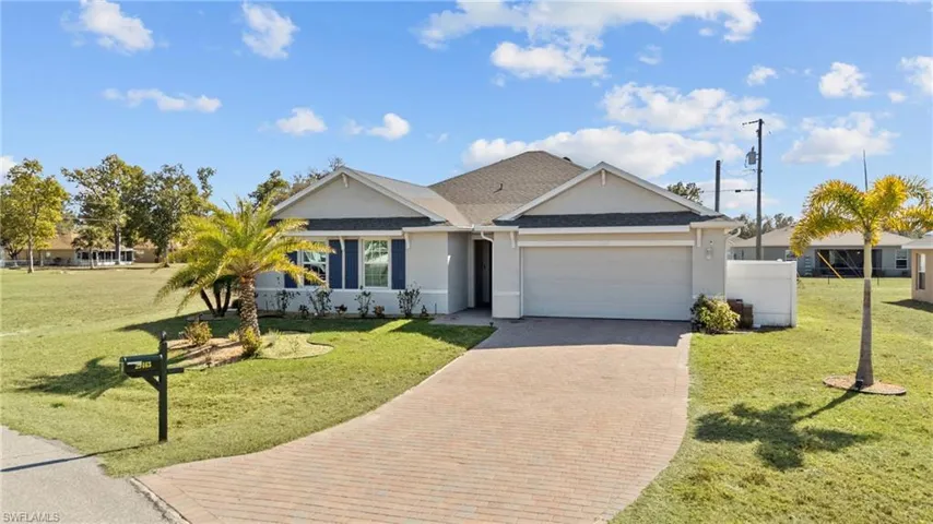 Ranch-style home with stucco siding, a garage, a front lawn, decorative driveway, and a shingled roof
