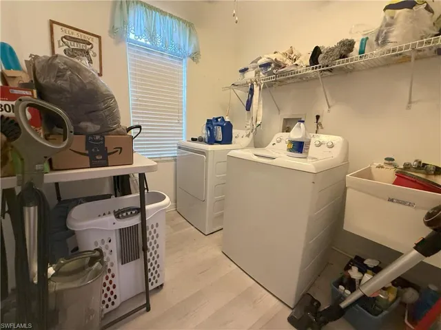 Clothes washing area featuring independent washer and dryer, light wood-type flooring, and sink