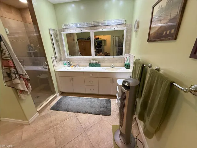 Master Bathroom with tile patterned floors, backsplash, vanity, and a shower with shower door