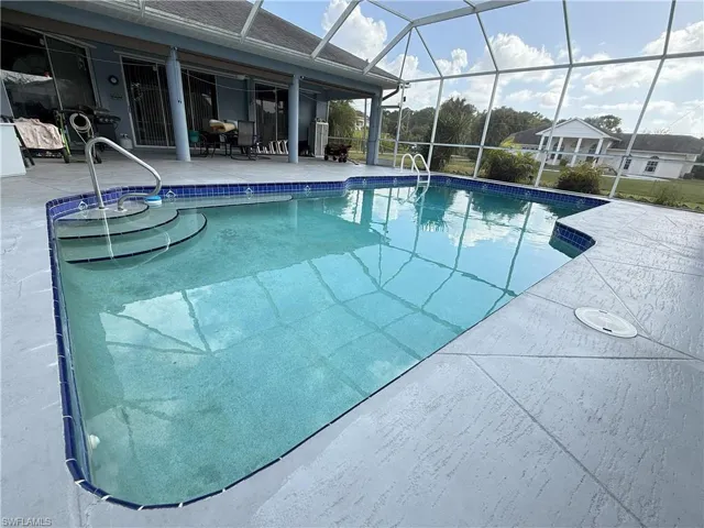 View of swimming pool featuring a patio area and glass enclosure