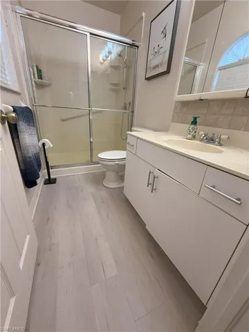 2nd Bathroom with tasteful backsplash, walk in shower, vanity, wood-type flooring, and toilet