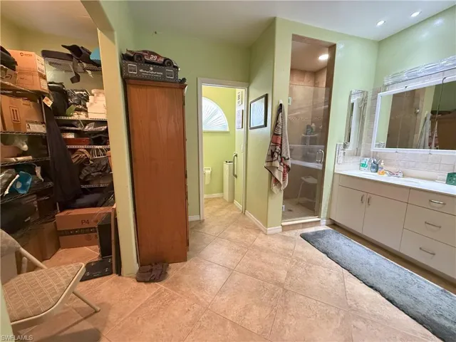 Master Bathroom with tile patterned flooring, vanity, a walk in master closet and an enclosed shower