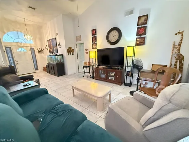 Tiled living room featuring high vaulted ceiling and a notable chandelier